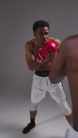 disparo de estudio de video vertical de dos boxeadores masculinos con guantes luchando en un partido de boxeo disparado en tiempo real 1