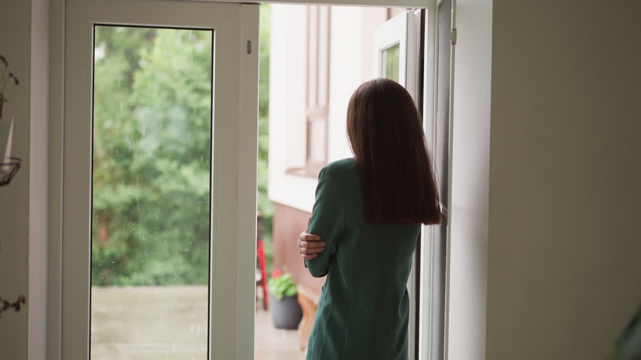 una mujer desesperada mira la lluvia por la ventana. el estado de ánimo de la mujer trabajadora se oscurece viendo las gotas de lluvia gotear por el vidrio de la ventana perdida en pensamientos deprimentes.