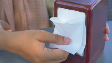 woman taking napkin from dispenser