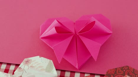 handmade pink origami paper heart on pink paper for valentines day