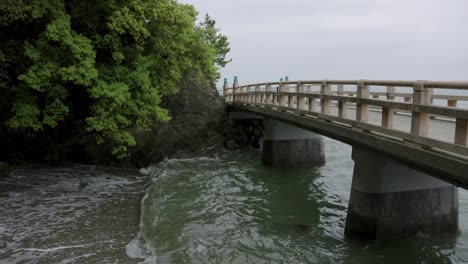 waves and bridge through meoto iwa shrine, mie prefecture japan