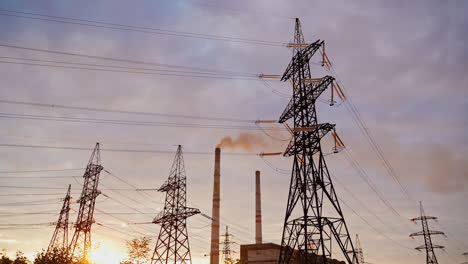 electricity pylons against orange and yellow sunset. selective focus. video from the side.