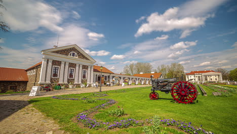 Iconic-Pakruojis-manor-and-old-equipment-nearby,-time-lapse-view