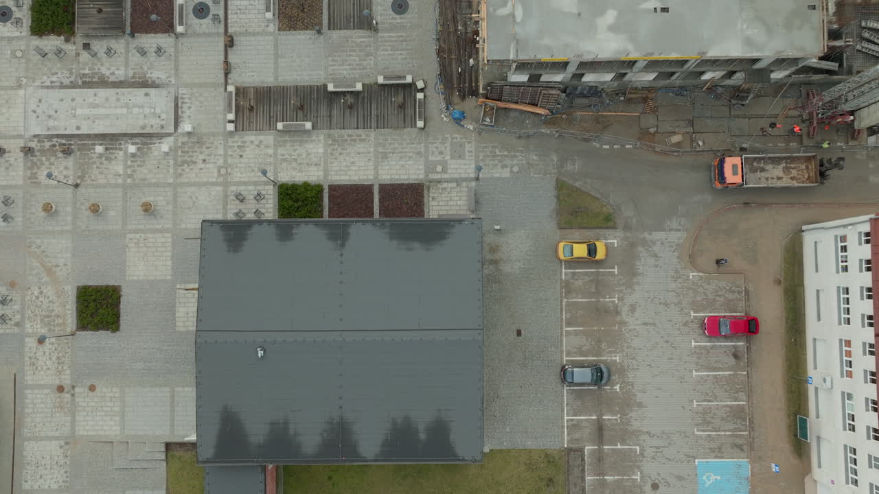 paisaje urbano desde una perspectiva aérea única, destacando los intrincados patrones de sitios de construcción, techos texturizados y vehículos estacionados que componen el ritmo diario de la vida de la ciudad