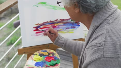 Close-up-of-african-american-senior-woman-painting-on-canvas-in-the-balcony-at-home