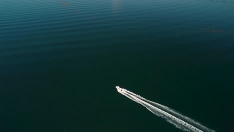 Tiro-De-Dron-Ascendente-De-Un-Barco-Que-Acelera-A-Través-De-La-Superficie-De-Un-Lago