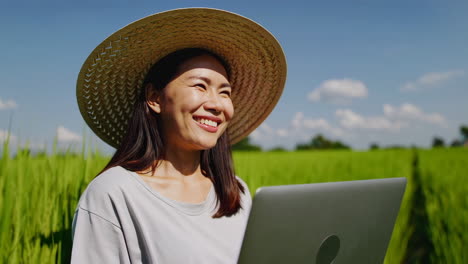 Female Farmer Using Laptop in Green Rice Field
