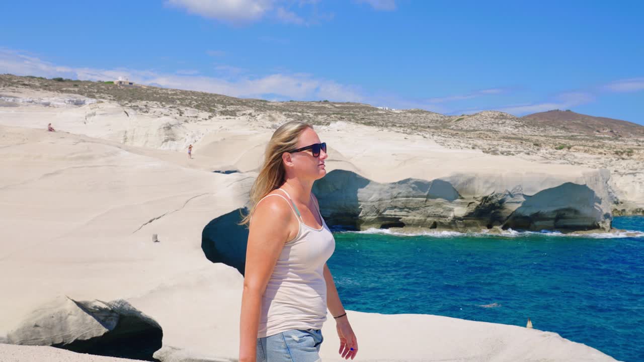 mujer caminando en cámara lenta en las formaciones rocosas volcánicas de la playa de sarakiniko en la isla de milos, grecia