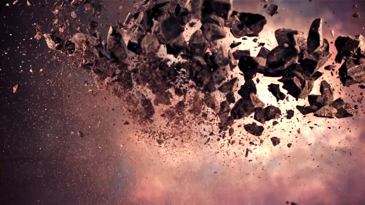 Esplosione al rallentatore di rocce scure e polvere contro un cielo nuvoloso