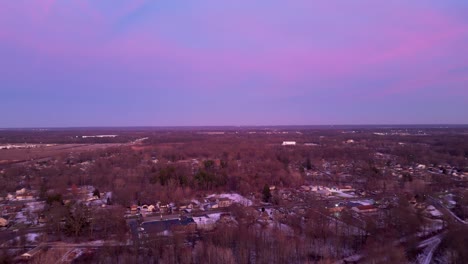 Drone-captures-twilight-hues-over-a-snow-dusted-suburb,-showcasing-winter's-serene-beauty-and-vibrant-skies