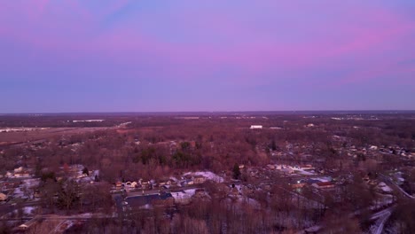 Drone captures twilight hues over a snow-dusted suburb, showcasing winter's serene beauty and vibrant skies