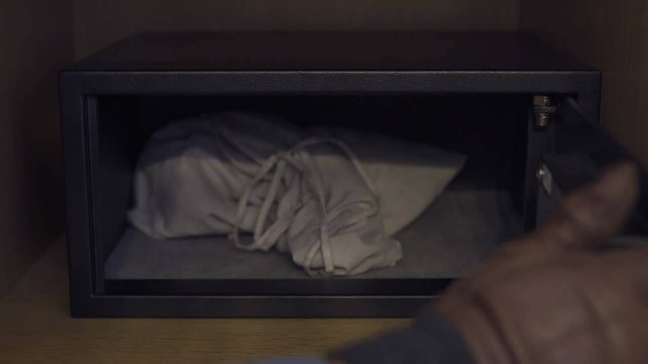 금고에 돈 가방을 숨기고 문을 닫는 도둑