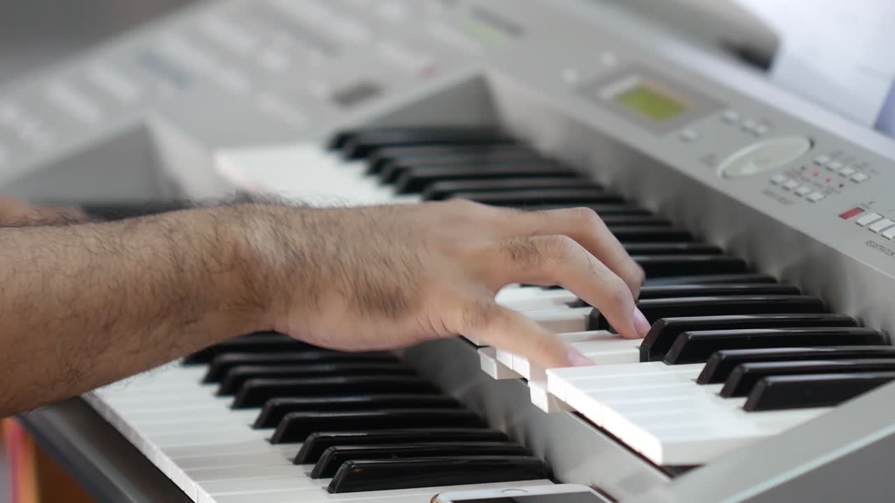 A man's hand is playing the keyboard keys. The concept of playing musical instruments