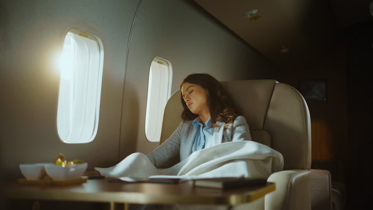 Woman sleeping on a private jet with flight attendant attending