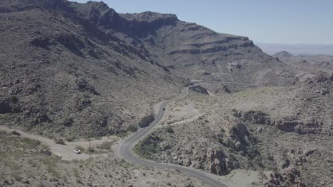 Toma-Aérea-De-Drones-De-Un-Automóvil-Que-Viaja-Por-Una-Carretera-Del-Desierto