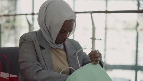 black woman with hijab checks up purchase in shopping mall