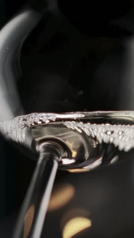 vertical video of white wine being pour in glass in super slow motion, extreme close-up