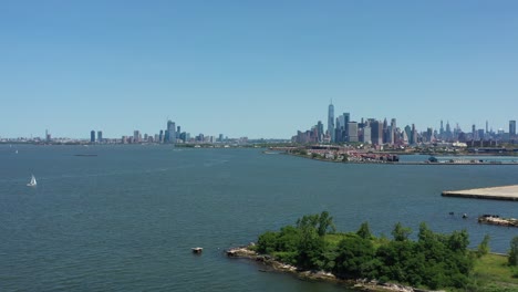 slow aerial dolly shot towards lower manhattan over upper new york bay with a little white sailboat in view