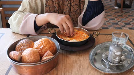 woman enjoying traditional turkish breakfast with eggs, bread and tea