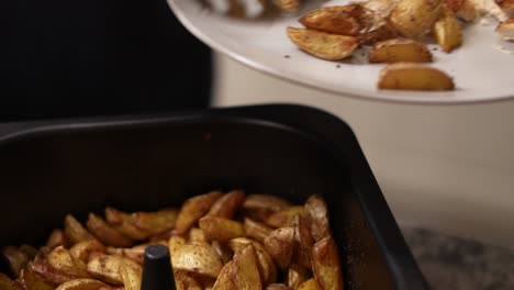 putting home cooked greek small potato wedges onto plate with serving spoon