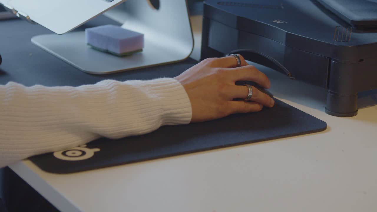 Dolly out of woman's hand using computer mouse in office