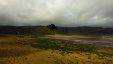 Aerial-landscape-view-of-a-glacier-river-with-many-branches-flowing-in-a-mountain-valley,-in-Iceland