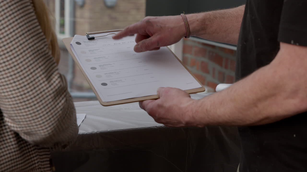 High Quality Video of two people discussing details on a clipboard. Hands pointing and engaging in consultation, highlighting teamwork and planning process