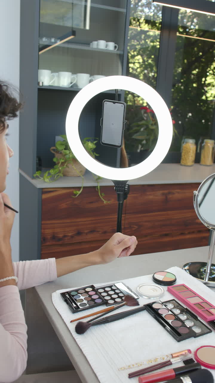 Vertical video: Applying makeup at home, person using smartphone and ring light for tutorial