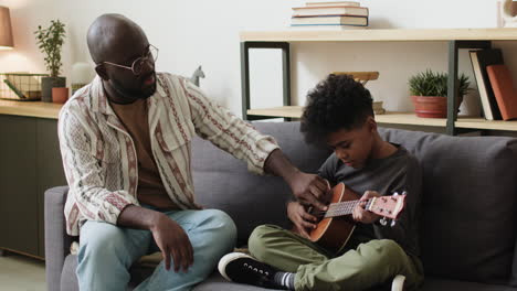 father and son learning how to play the ukulele