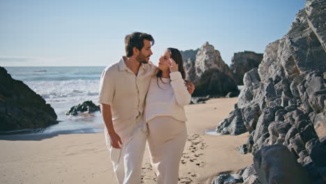 expectant father mother walking beautiful rocky shore hugging together close up.