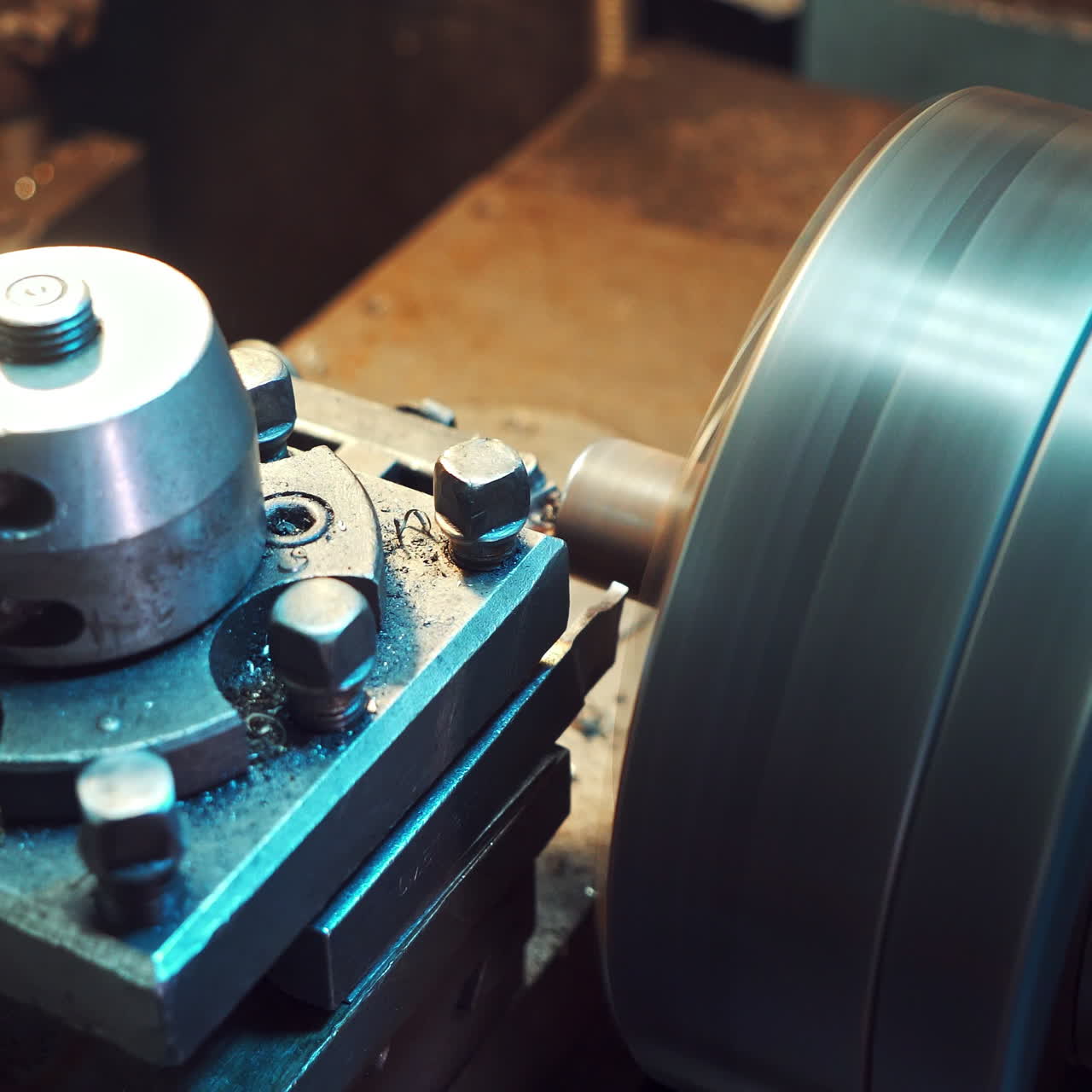 A detail is cutting with using a rotating lathe producing remnants of metal shavings in the plant. Close-up.