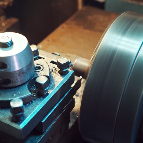 a detail is cutting with using a rotating lathe producing remnants of metal shavings in the plant. close-up.