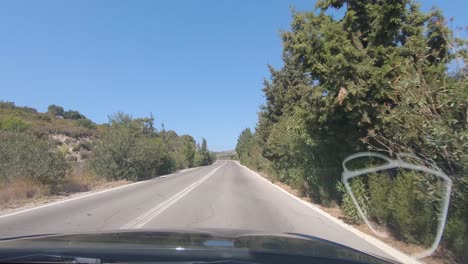 Watching-out-of-the-front-window-of-a-car,-while-driving-free-at-the-roads-of-Rhodes-island,-Greece-in-beautiful-weather-conditions