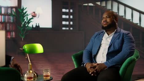 two business associates sip whiskey while discussing corporate success