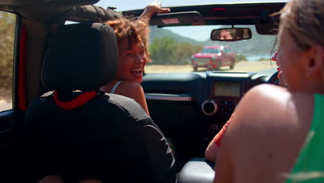 Group-Of-Laughing-Female-Friends-Having-Fun-In-Open-Top-Car-On-Road-Trip