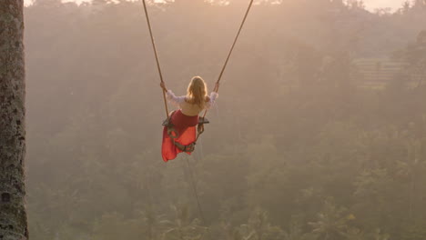 travel-woman-swinging-over-tropical-rainforest-at-sunrise-female-tourist-sitting-on-swing-with-scenic-view-enjoying-freedom-on-vacation-having-fun-holiday-lifestyle-slow-motion