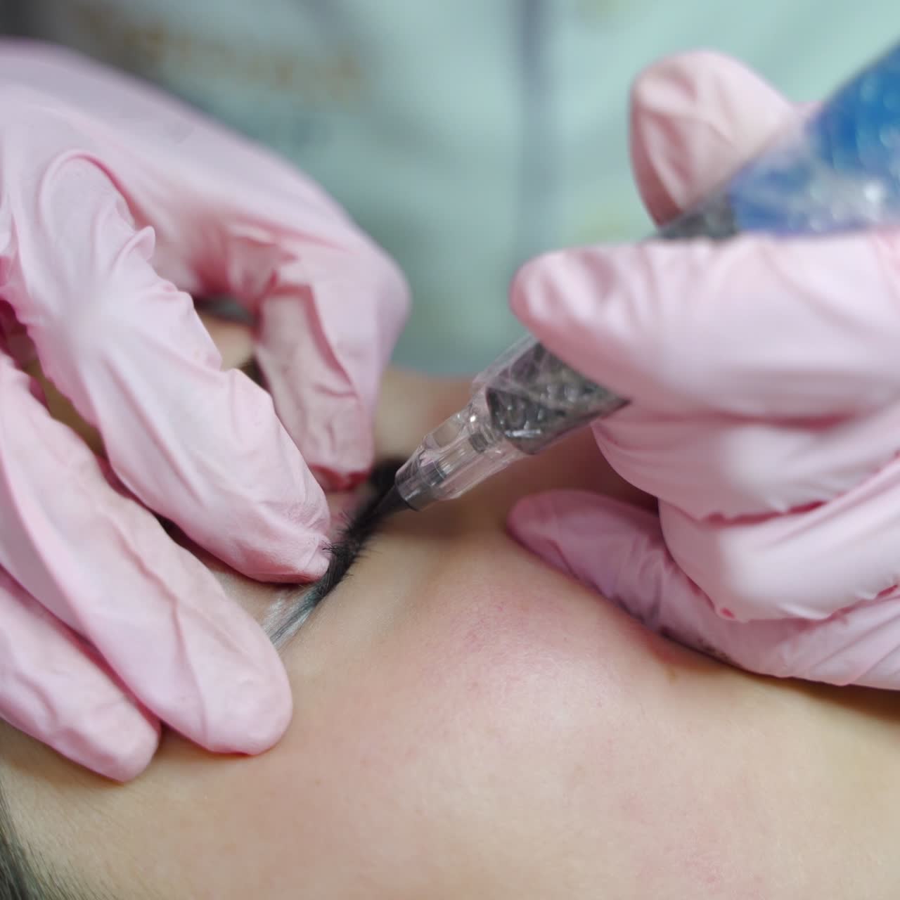 procedure of permanent makeup of eyes for women. The master is painting the client's eyes with a professional brush with a needle.