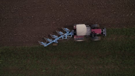 Top-down-of-an-older-tractor-plows-a-field-in-spring-on-a-cloudy-day