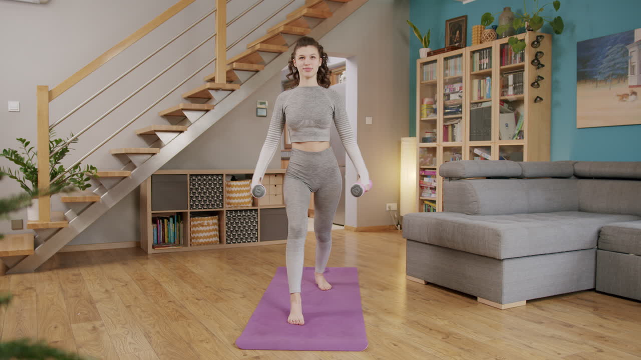 joven morena enérgica entrenando hombros con pesas haciendo ejercicio físico en casa