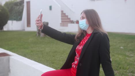 Girl-wearing-a-surgical-mask-on-her-face-and-taking-a-selfie-outside