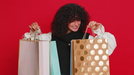 woman showing shopping bags advertising purchase discounts smiling looking amazed with low prices