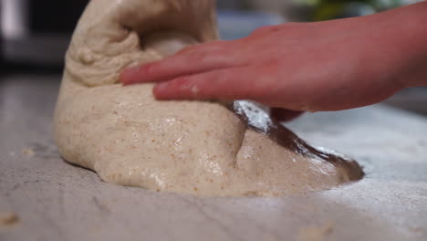 joven chef masculino formando masa fermentada y amasando y volviendo a colocar en un recipiente de plástico para demostrar que está listo para hornear más tarde