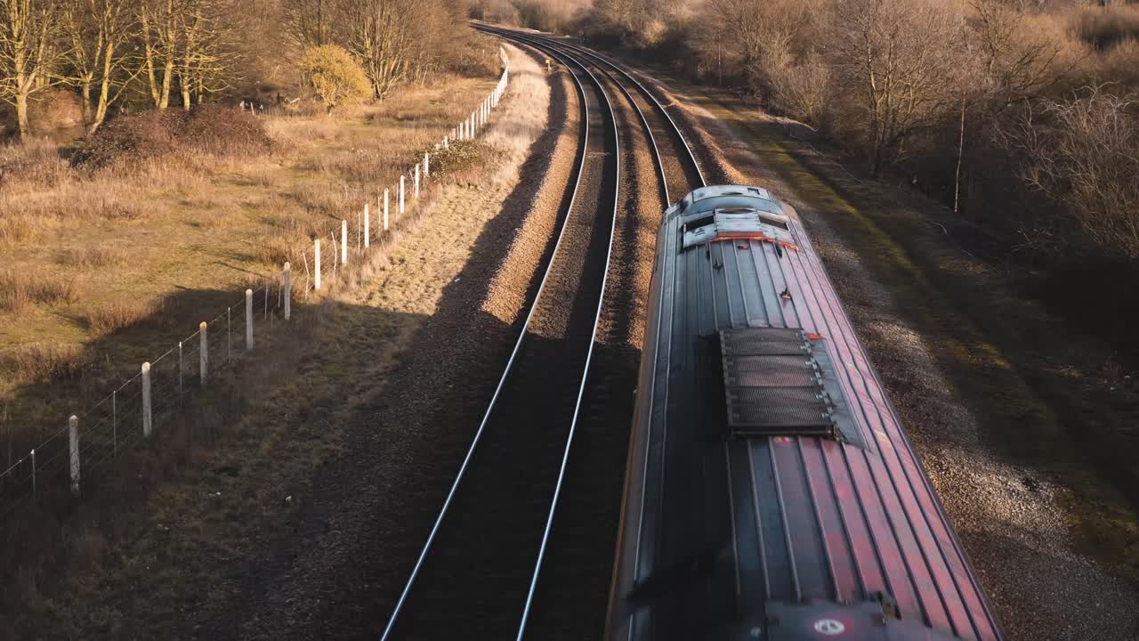 un pequeño tren de pasajeros que pasa por debajo de un puente peatonal