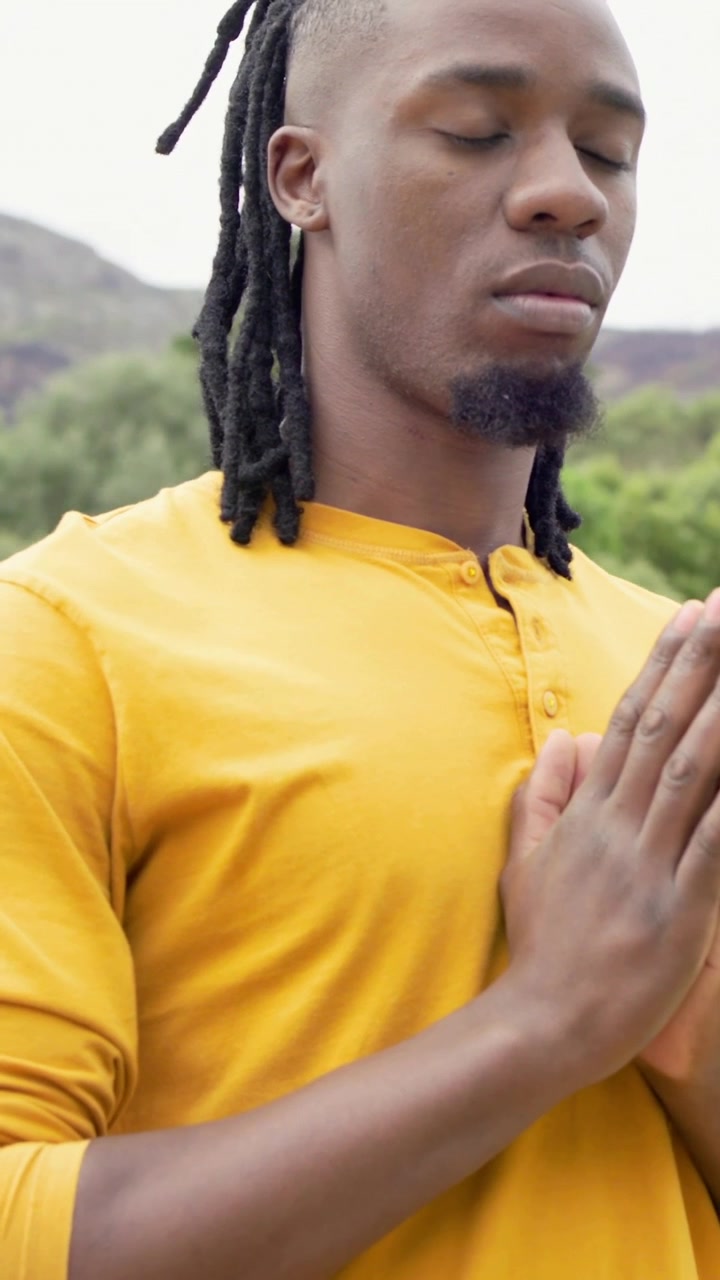 Vertical video: Opening shot showing man meditating on balcony with yoga ball prop, finding calm