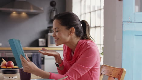 Beautiful-mixed-race-woman-talking-to-boyfriend-over-internet-using-digital-tablet-app-at-home-in-kitchen