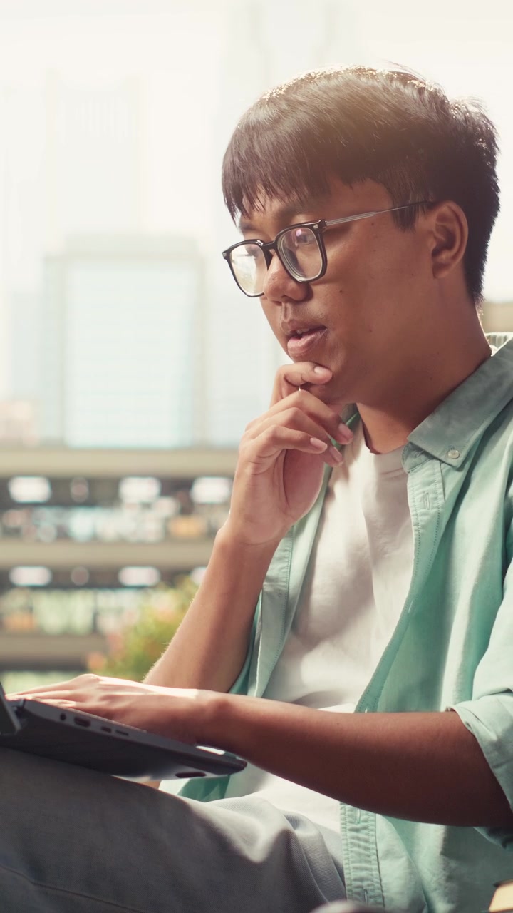 Vertical Video Young student brainstorming ideas on laptop sitting on bench