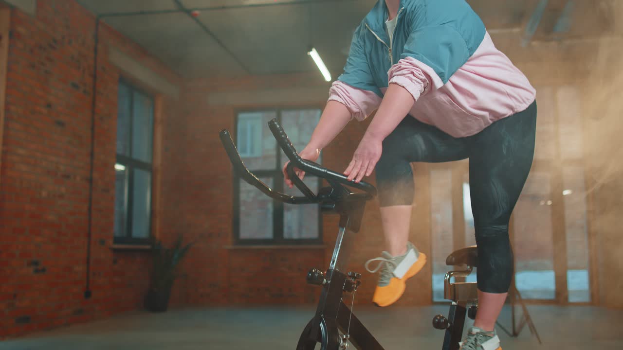 안개 가득한 체육관 에서 자전거 를 타고 에어로빅 라이딩 훈련 을 하는 운동 여자