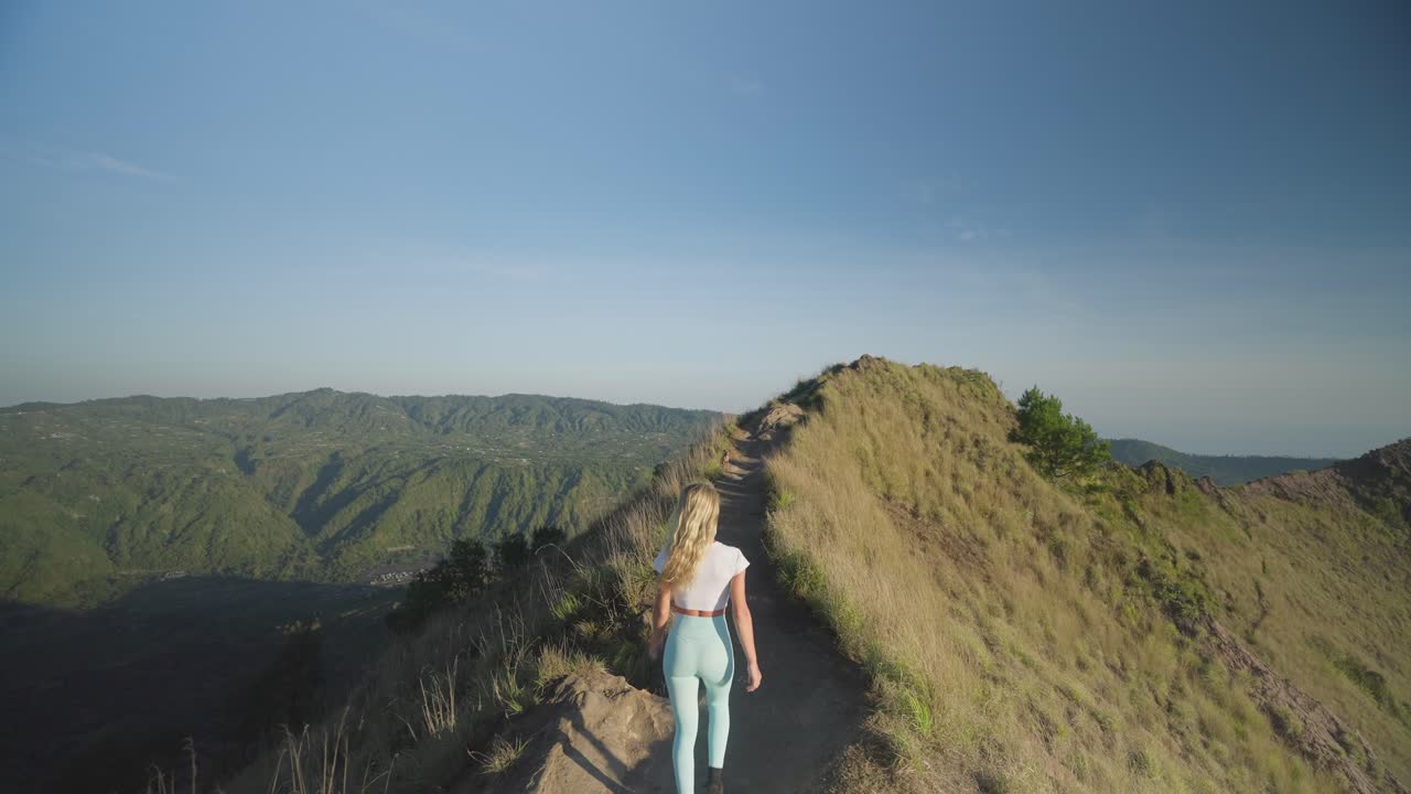 mujer rubia viajera senderismo en la cresta del monte batur al amanecer en bali