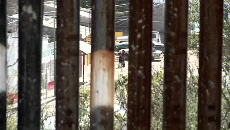 two people down in a poor intercity community are being observed through the slats of a border fence