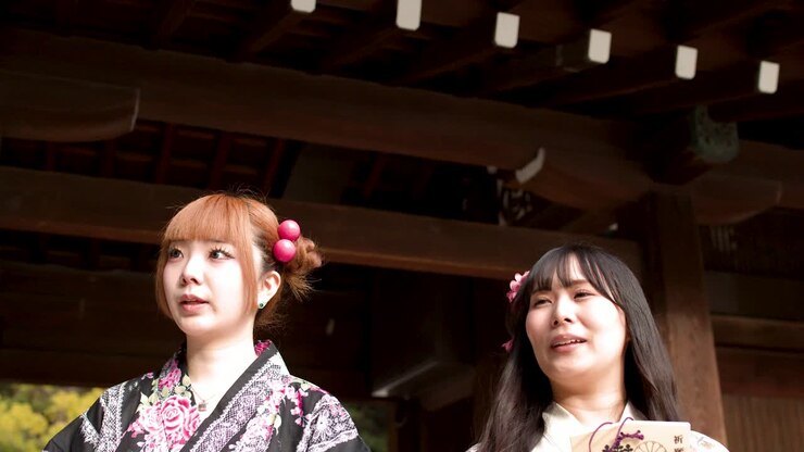 Due giovani donne in kimono tradizionali tengono placche ema di legno mentre visitano un santuario di Tokyo.
